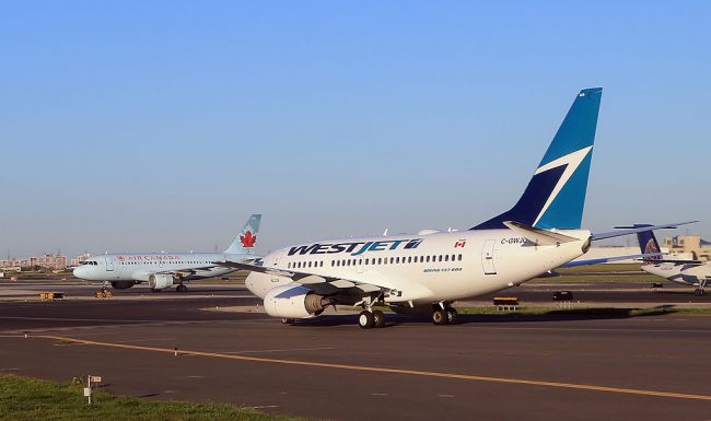 A WestJet flight and an Air Canada flight cross paths on a runway at Toronto's Lester B. Pearson airport as photographed from an airplane on Aug. 28, 2012.