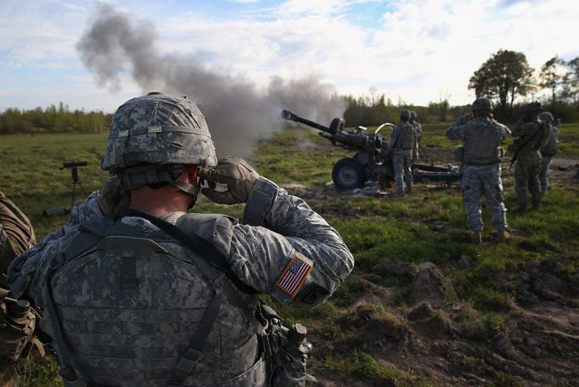 A 10th Mountain Division soldier plugs his ears while comrades fire a 105mm Howitzer during a training mission for future conflicts on May 18, 2016 at Fort Drum, New York. 