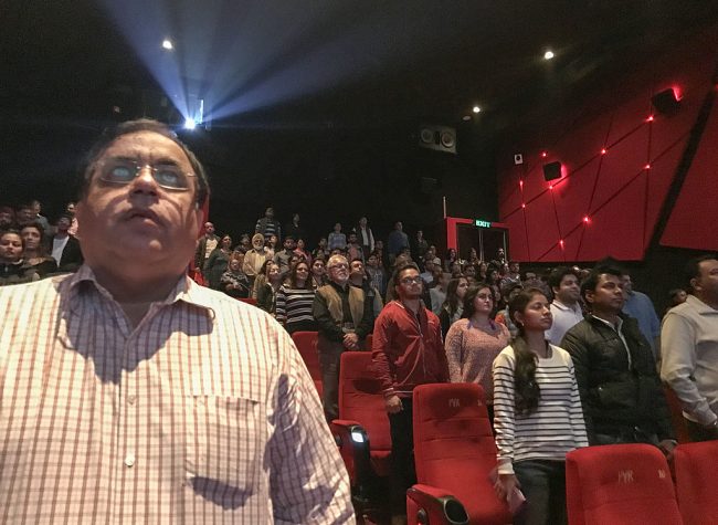 Audience members stand for the Indian national anthem before a movie starts at a cinema in New Delhi on December 4, 2016. 