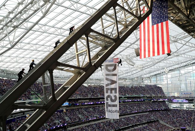 Three firemen and a police officer scale the rafters of US Bank Stadium where two protestors of the Dakota Access Pipeline hang suspended above the Minnesota Vikings and Chicago Bears football game on January 1, 2017 in Minneapolis, Minnesota.