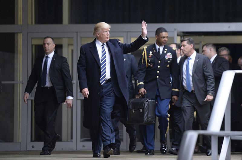 U.S. President Donald Trump leaves CIA headquarters on January 21, 2017 in Langley, Virginia. In the background a military officer carries the ‘football’, with launch codes for nuclear weapons.