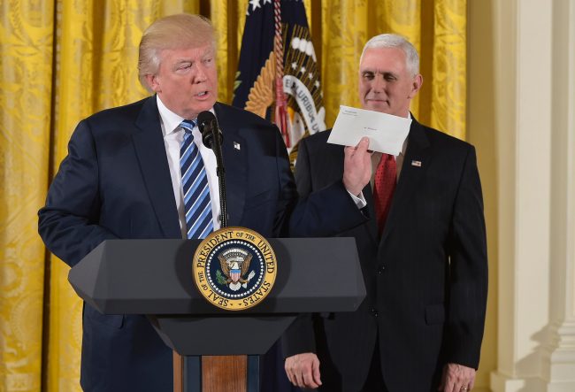 US President Donald Trump holds the letter left for him by former US President Barack Obama, as Vice President Mike Pence watches, before the swearing in of the White House senior staff at the White House on January 22, 2017, in Washington, DC. 