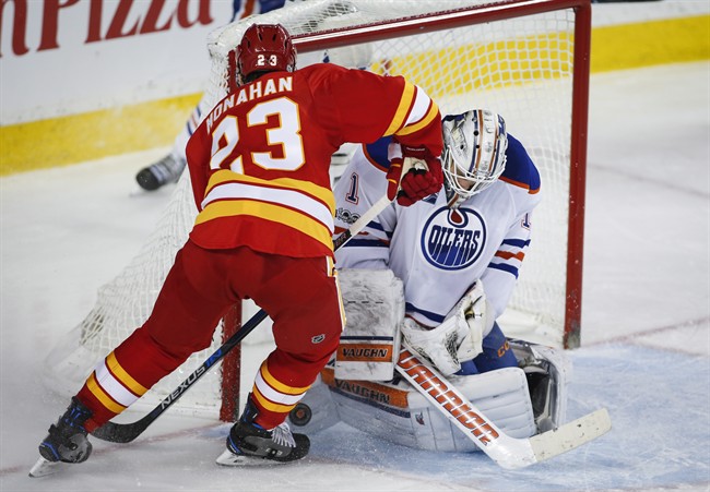 Edmonton Oilers' goalie Laurent Brossoit, right, stops Calgary Flames' Sean Monahan during third period NHL hockey action in Calgary, Saturday, Jan. 21, 2017.