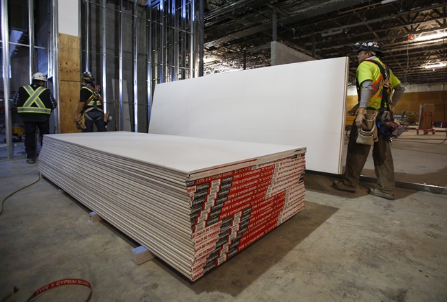 Construction workers move sheets of drywall at a building project in Calgary, Alta., Friday, Dec. 30, 2016. Anti-dumping duties on U.S. drywall imports into Western Canada have hiked prices for the building product but have also resulted in new manufacturing jobs, says the company whose complaint prompted the trade tariffs. CertainTeed Gypsum Canada has added about 30 employees since duties began in September at its drywall plants in Vancouver, Calgary and Winnipeg to boost production, said spokesman Mike Loughery in an email. 