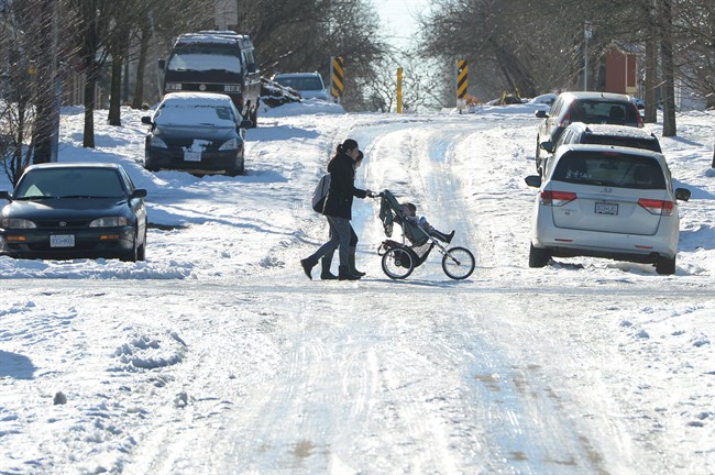 A woman pushes a stroller on an ice-covered street in Vancouver, Tuesday, Jan.3, 2017. 