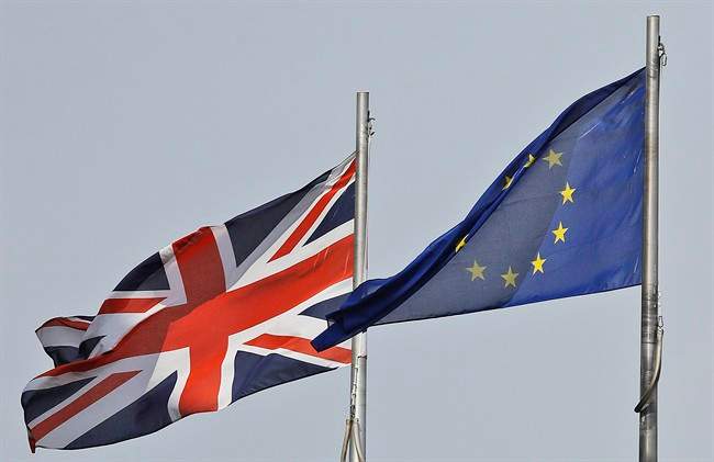 In this Thursday, Aug. 18, 2016 file photo, a Union Jack flag and a European flag blow in the wind in front of the city hall in London. 