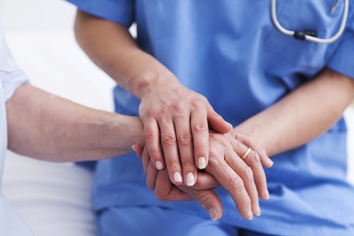 File photo of a nurse touching hand of a patient in hospital ward.
