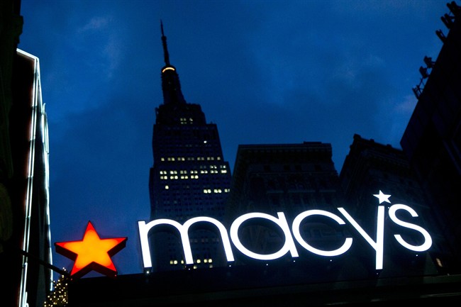 FILE - In this Nov. 21, 2013, file photo, with the Empire State building in the background, the Macy's logo is illuminated on the front of the department store in New York.
