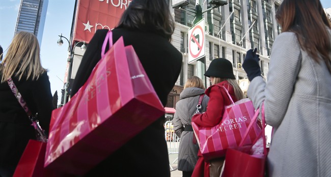 FILE - In this Saturday, Nov. 23, 2013, file photo, shoppers carry Victoria Secret bags while crossing an intersection in Herald Square in New York. 