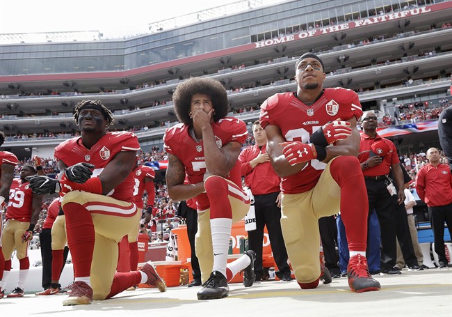 FILE - In this Oct. 2, 2016, file photo, from left, San Francisco 49ers outside linebacker Eli Harold, quarterback Colin Kaepernick and safety Eric Reid kneel during the national anthem before an NFL football game against the Dallas Cowboys in Santa Clara, Calif.