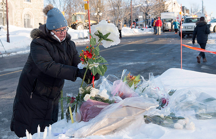 A woman places flowers near a mosque where a Sunday night shooting left six people dead, Monday, January 30, 2017 in Quebec City. 