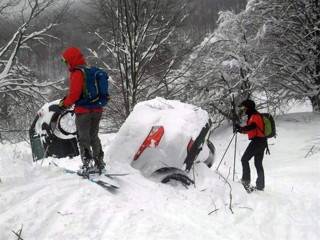 Rescuers stand by two cars submerged in snow as they work in front of the Rigopiano Hotel, following an avalanche in Farindola, Italy, early Thursday, Jan. 19, 2017. (Corpo Nazionale Soccorso Alpino e Speleologico/The National Alpine Cliff and Cave Rescue Corps (CNSAS) via AP).