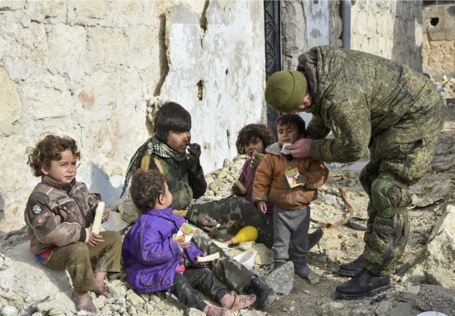 This undated handout photo released by the Russian Defense Ministry claims to show a Russian Military engineer distributing juice to local children in Aleppo, Syria. Guns have fallen silent in the eastern part of the city, and for now, that's enough to create a sense of optimism, says a UN official.