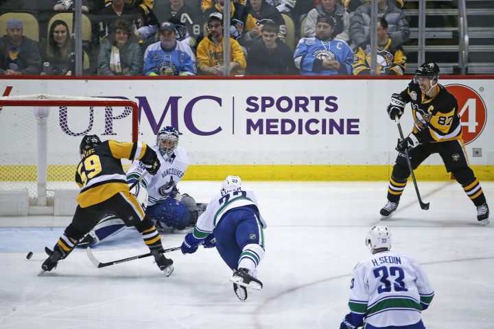 Pittsburgh Penguins' Jake Guentzel (59) takes a pass from Sidney Crosby (87) and puts the puck behind Vancouver Canucks goalie Ryan Miller (30) for a goal with Alexander Edler (23) defending during the third period of an NHL hockey game in Pittsburgh, Tuesday, Feb. 14, 2017. It was Crosby's 999th career point in the NHL. The Penguins won 4-0. 