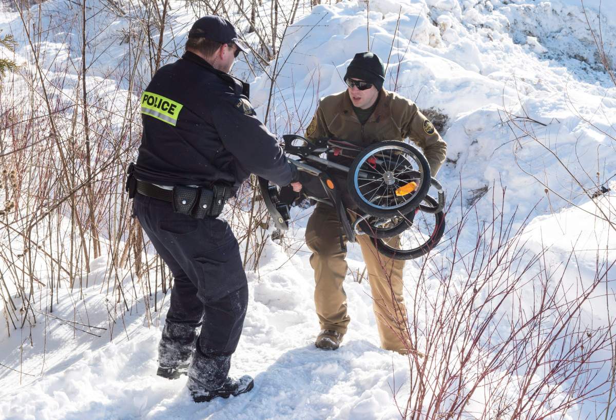 A U.S. Border Patrol agent passes a baby carriage to an RCMP officer left over after a Somalian family crossed the U.S.-Canada border into Canada near Hemmingford, Que., on Friday, Feb. 17, 2017.