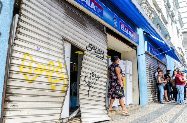 A woman walks past by the entrance of an appliance store damaged after gang attacks in Vitoria, Espirito Santo state, Brazil February 6, 2017. 