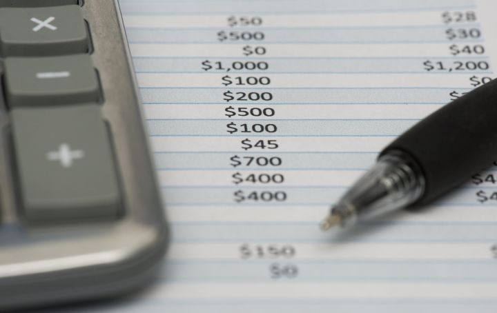 A calculator, expense sheet and a pen are shown. 