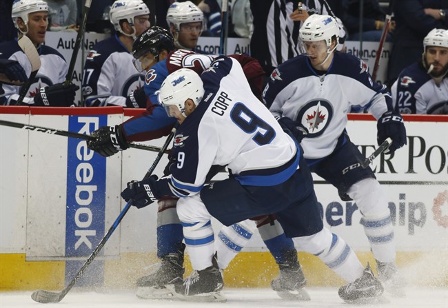 Winnipeg Jets centre Andrew Copp clears the puck from the boards as Colorado Avalanche left wing Andreas Martinsen and Jets defenceman Jacob Trouba look on during an NHL game on Feb. 4, 2017 in Denver.