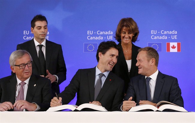 Canadian Prime Minister Justin Trudeau, center front, sits with European Commission President Jean-Claude Juncker, left, and European Council President Donald Tusk, right, as they sign the Comprehensive Economic and Trade Agreement (CETA) during an EU-Canada summit at the European Council building, in Brussels in an October 30, 2016, file photo.