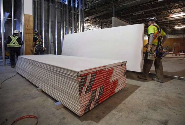 Construction workers move sheets of drywall at a building project in Calgary, Alta., on December 30, 2016. 