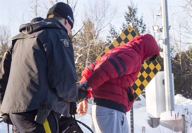 A young man from Yemen is handcuffed by an RCMP officer after crossing the U.S.-Canada border into Canada near Hemmingford, Que., on Friday, February 17, 2017.