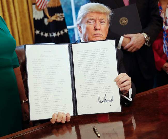 President Donald Trump holds up an executive order after his signing the order in the Oval Office of the White House in Washington, Friday, Feb. 3, 2017.