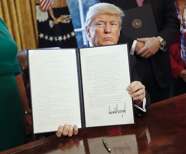 President Donald Trump holds up an executive order after his signing the order in the Oval Office of the White House in Washington, Friday, Feb. 3, 2017.