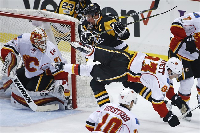 Pittsburgh Penguins' Sidney Crosby (87) collides with Calgary Flames' Sam Bennett (93) in front of Flames goalie Chad Johnson (31) during the first period of an NHL hockey game in Pittsburgh, Tuesday, Feb. 7, 2017. 