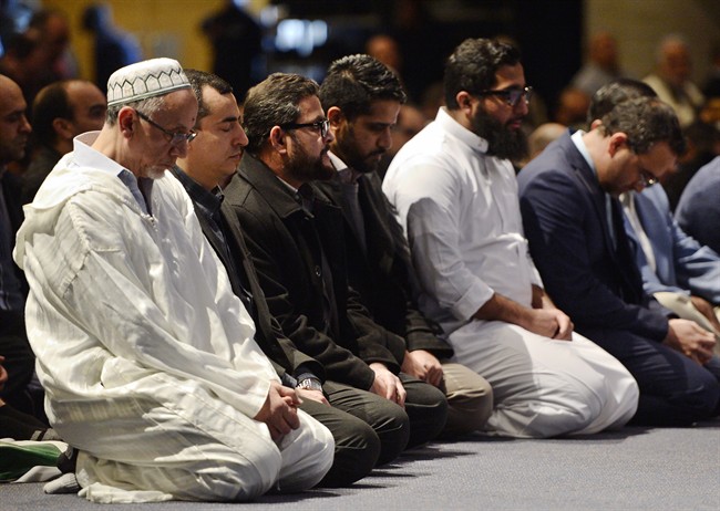 People pray at a funeral service for three of the six victims of the Quebec City mosque shooting at the Quebec City convention centre Friday, February 3, 2017.