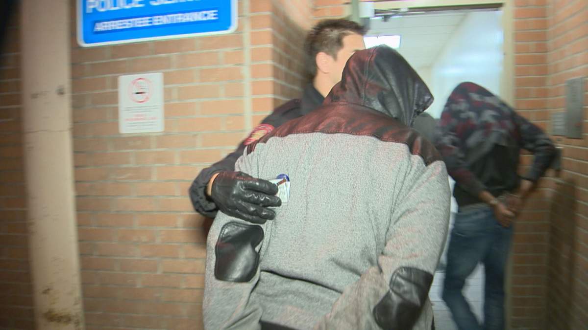 Calgary police escort two men into the arrest processing unit on Feb. 7, 2017. 