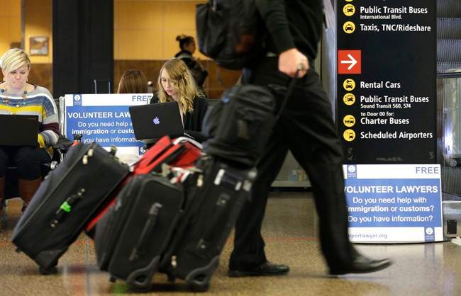 Asti Gallina, center, a volunteer law student from the University of Washington, works at a station near where passengers arrive on international flights at Seattle-Tacoma International Airport Tuesday, Feb. 28, 2017, in Seattle.