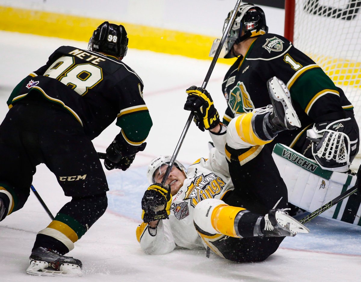London Knights' Victor Mete, left, upends Brandon Wheat Kings' Tyler Coulter centre, in front of goalie Tyler Parsons during first period CHL Memorial Cup hockey action in Red Deer, Monday, May 23, 2016.THE CANADIAN PRESS/Jeff McIntosh.