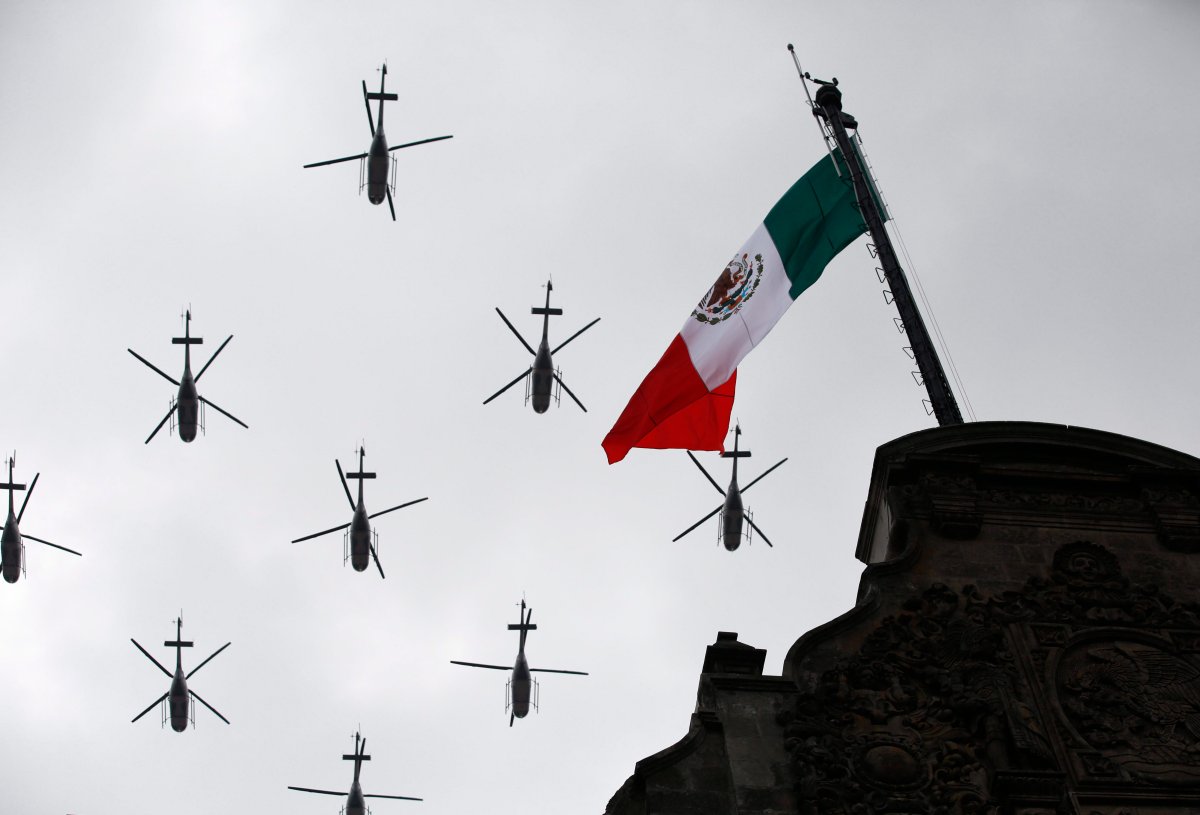 Military helicopters fly past the Mexican flag atop the National Palace, during the annual Independence Day military parade in Mexico City's main square, known as the Zocalo, Friday, Sept. 16, 2016.