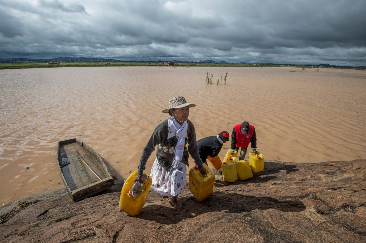 Residents cross flooded land and canal in Madagascar's capital Antananarivo, on Friday, March 10, 2017, to collect fresh water.  Cyclone Enawo hit land Tuesday, claiming the lives of at least five people and forcing some 10,000 people abandon their homes because of storm damage. 