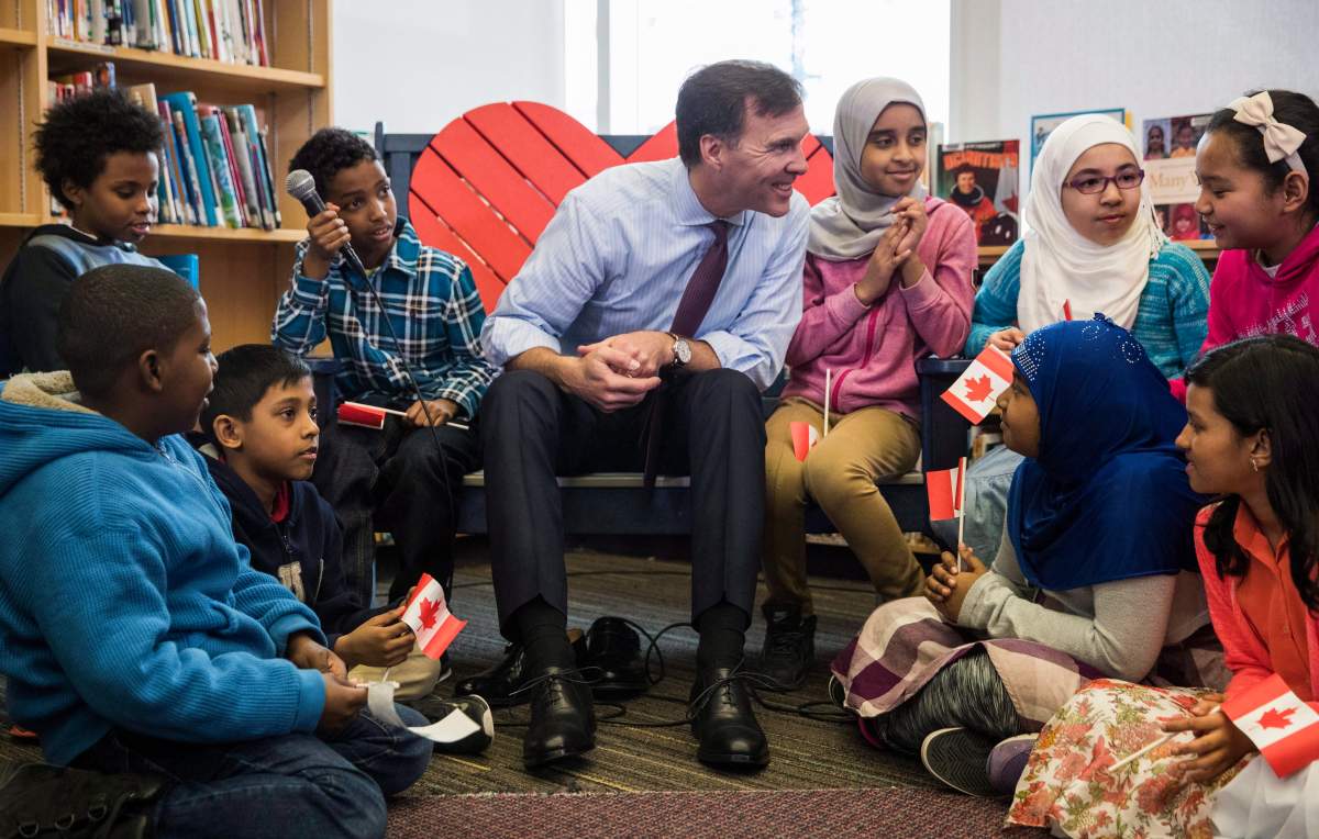 Federal Finance Minister Bill Morneau talks to students after taking part in the pre-budget ceremony of putting on new shoes at the Nelson Mandela Park Public School in Toronto, Monday March 20, 2017.