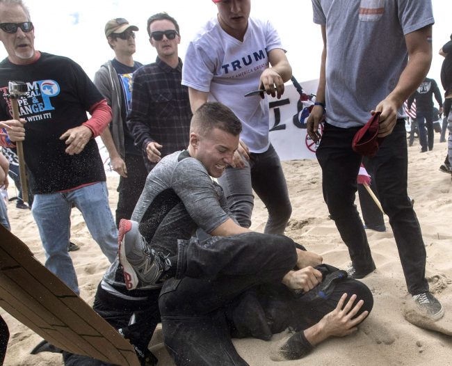A Donald Trump supporters clashes with an anti-Trump protester, bottom, who allegedly pepper sprayed the organizer of a pro-Trump rally in Huntington Beach, Calif.,, March 25, 2017.