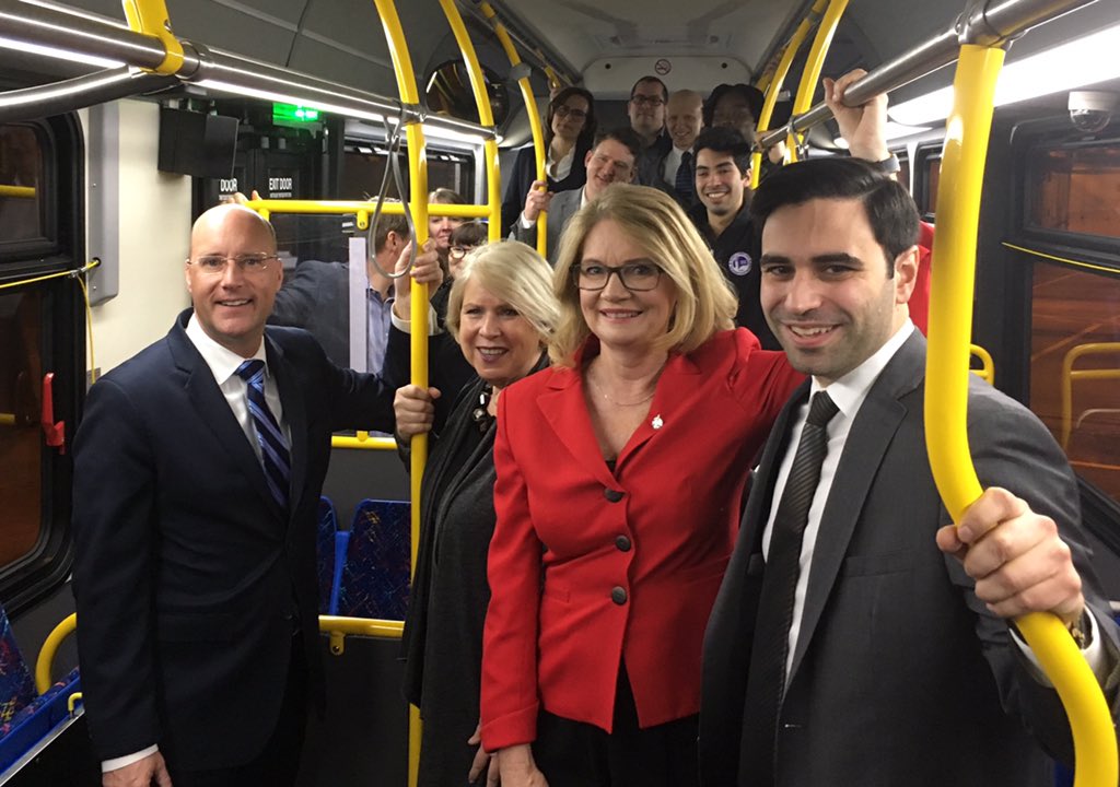MPs Peter Fragiskatos and Kate Young, Deputy Premier Deb Matthews, Mayor Matt Brown, and city councillors pose for a photo aboard an LTC bus.