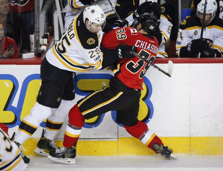 Boston Bruins' Brandon Carlo, left, checks Calgary Flames' Alex Chiasson during first period NHL hockey action in Calgary, Wednesday, March 15, 2017. 