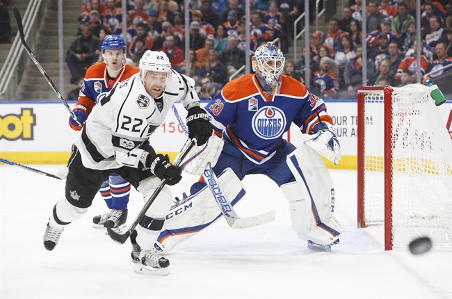 Edmonton Oilers' goaltender Cam Talbot (33) keeps his eye on the puck as Los Angeles Kings' Trevor Lewis (22) races for possession during third period NHL action in Edmonton, Alta., on Monday, March 20, 2017. 