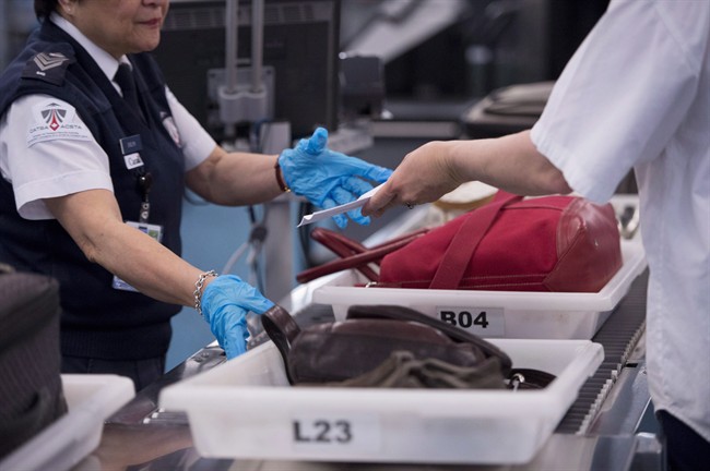 Canada's secretive cyberspies have turned to the people who pat travellers down at the airport to bolster security at their new Ottawa headquarters amid heightened concern about sensitive leaks. A CATSA employee performs security checks of passengers and their carry-on luggage at a security screening area at Vancouver International Airport in Richmond, B.C., in a February 6, 2017, file photo. THE CANADIAN PRESS/Jonathan Hayward.