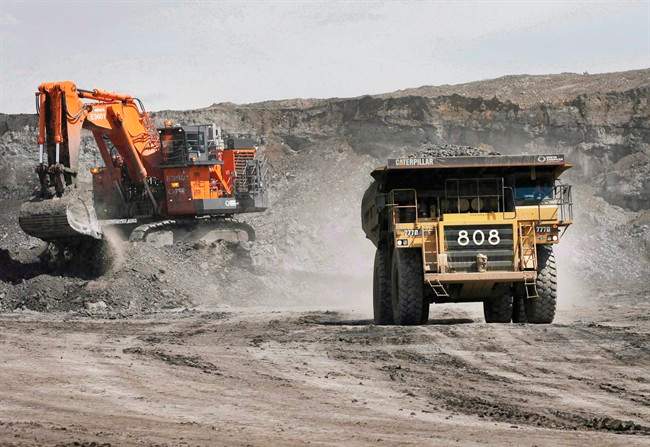 A haul truck carrying a full load drives away from a mining shovel at the Shell Albian Sands oilsands mine near Fort McMurray, Alta., on Monday.July 9, 2008.