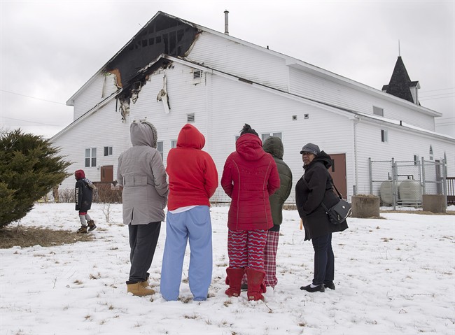 Members of the community look on as firefighters battle hotspots after a fire damaged St. Thomas Baptist Church in North Preston, N.S. on Wednesday, March 22, 2017. The pastor of an historic church in a community just east of Halifax says his congregation will soon work out a plan to rebuild after a fire caused extensive damage to the large structure.