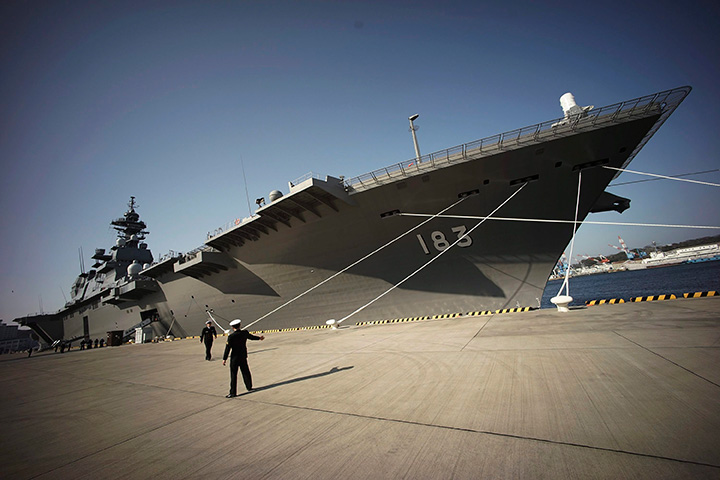 In this March 31, 2015 file photo, Self-Defence Forces personnel are photographed in front of the Izumo destroyer of Japan's Maritime Self-Defense Force in Yokosuka, south of Tokyo. 