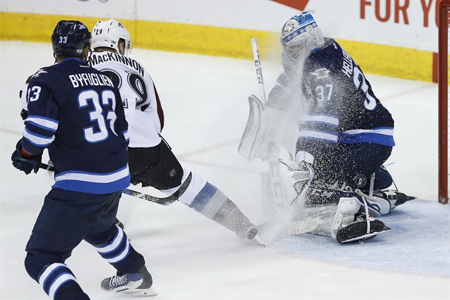 Despite the face-wash by Colorado Avalanche's Nathan MacKinnon (29) Winnipeg Jets goalie Connor Hellebuyck (37) stops the shot as Dustin Byfuglien (33) defends during third period NHL action in Winnipeg on Saturday, March 4, 2017. THE CANADIAN PRESS/John Woods.