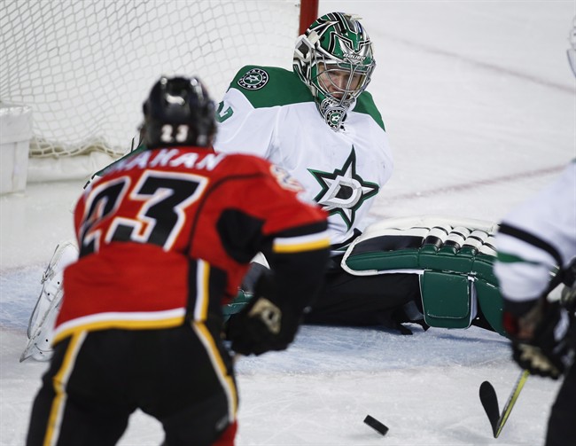 Dallas Stars goalie Kari Lehtonen, right, of Finland, loses his balance as Calgary Flames' Sean Monahan chases as rebound during third period NHL hockey action in Calgary, Friday, March 17, 2017.