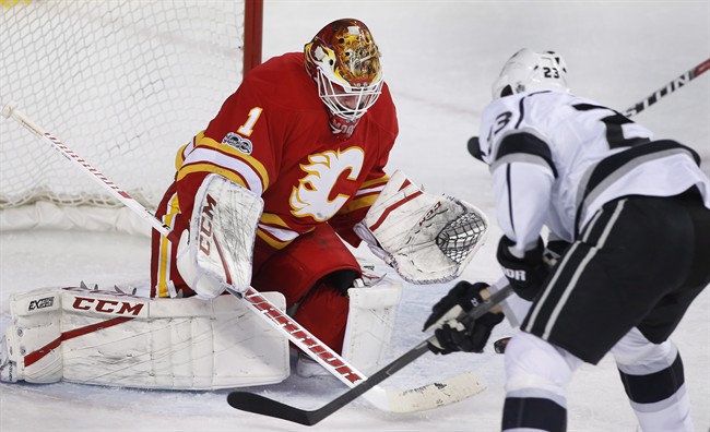 Calgary Flames goalie Brian Elliott, left, makes a save against Los Angeles Kings' Dustin Brown during second period NHL action in Calgary, Alta., Sunday, March 19, 2017. 