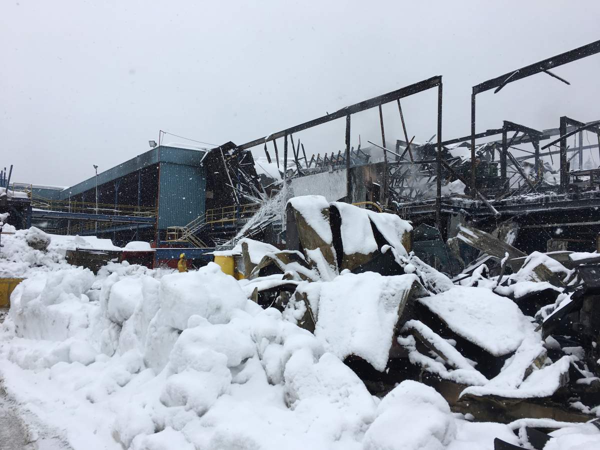 Firefighters spray hot spots the day after a major blaze at the Elite Forest Products mill in Malakwa.