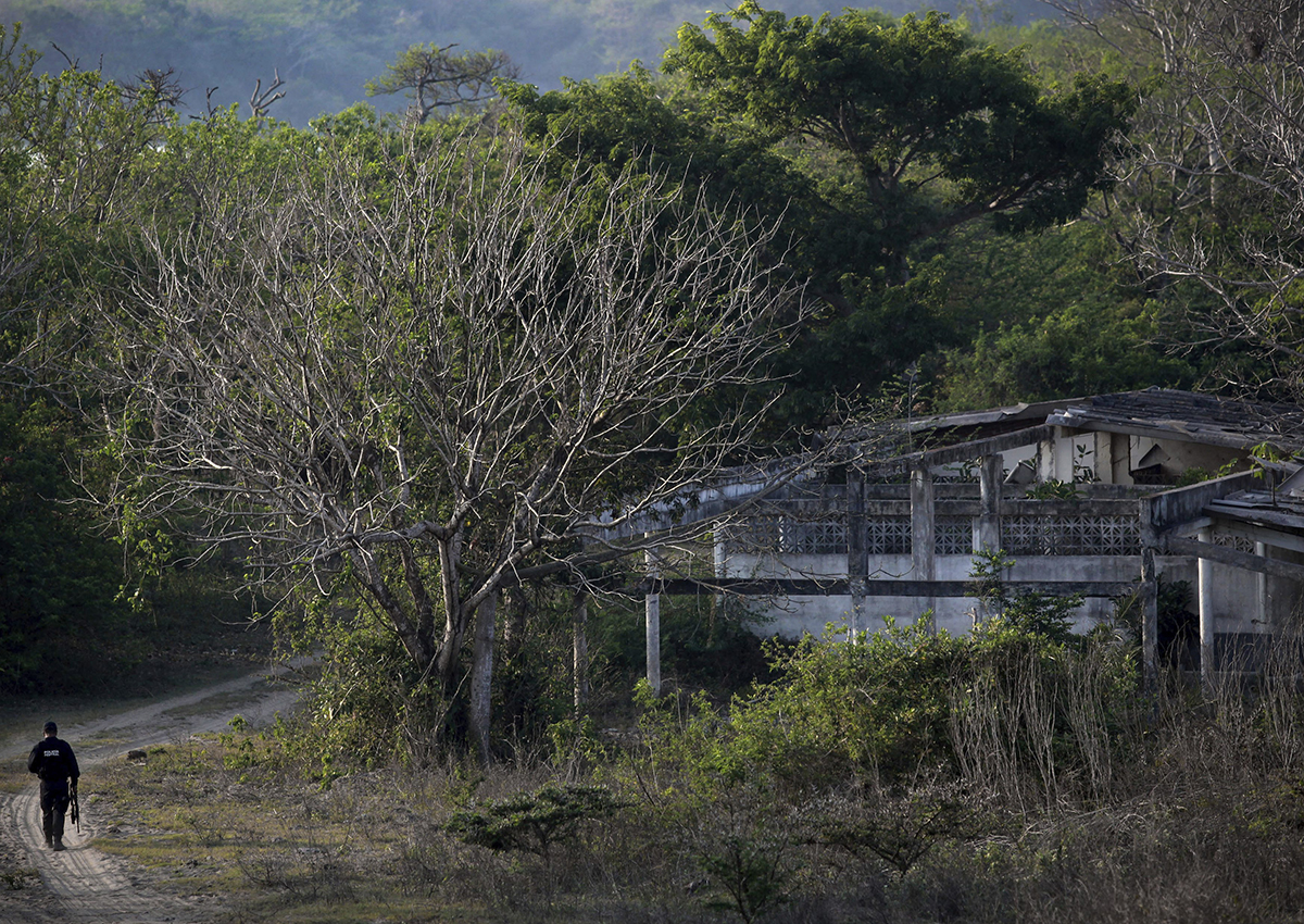 In this April 11, 2015 photo, a federal police officer walks in an area known as Colinas de Santa Fe on the outskirts of Veracruz, Mexico. 