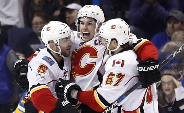 Calgary Flames' Sean Monahan, centre, is congratulated by teammates Mark Giordano (5) and Michael Frolik, of the Czech Republic, after scoring the game-winning goal during overtime of an NHL hockey game against the St. Louis Blues Saturday, March 25, 2017, in St. Louis. The Flames won 3-2 in overtime.