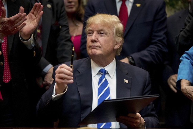 In this Monday, March 27, 2017, file photo, President Donald Trump holds up a pen he used to sign one of various bills in the Roosevelt Room of the White House in Washington.